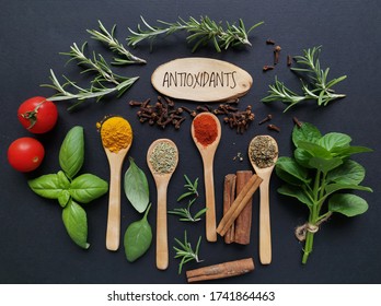 Set of various spices in wooden spoons and fresh herbs rich in antioxidants. Natural sources of antioxidants rosemary twigs, fresh green basil leaf, mint leaf, turmeric, clove, cinnamon, chili, tomato