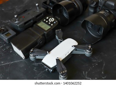 Set Of Videographer On A Black Background. Digital Camera, Memory Card, Action Camera, Drone, Remote Control And Camera. Top View On Black Background Table.