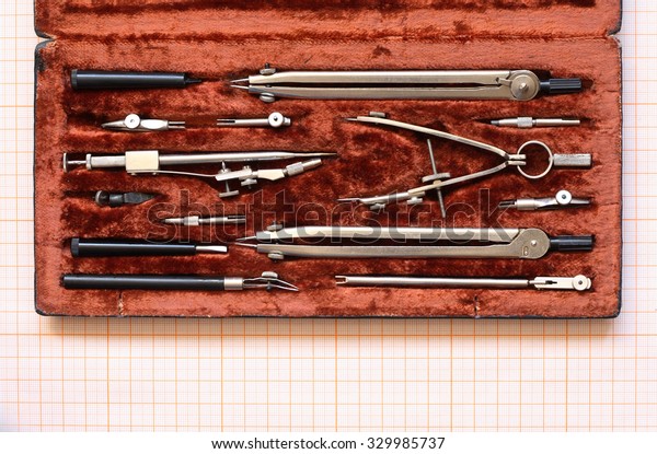 Set\
of vintage drawing instrument in box on graph\
paper
