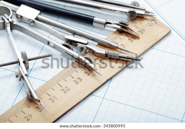 Set of vintage drawing instrument and ruler on\
graph paper