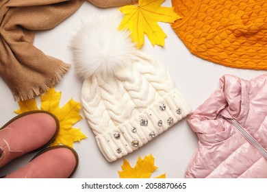 A set of warm autumn-winter clothes with fallen maple leaves on a white background. Hat jacket scarf boots sweater. Flat lay top view