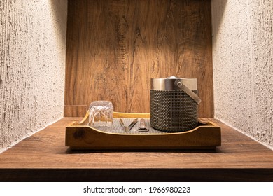 A set of whiskey or brandy drinking utensils such as glass, cooler box, bottle opener and ice tong which is prepared in the wooden tray. Interior decoration and object. Selective focus photo.