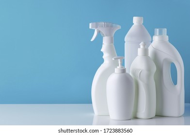 Set of white bottles of different cleaning procucts on blue background with empty space for text