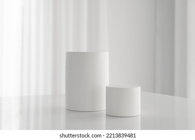 Set of white cylinder pedestal podium on white table in white background and curtain texture. A stage for showcase, and display. Suitable for product presentation backdrop, banner, and mockup.