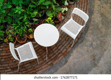 A Set Of White Plastic Chairs And Table In The Garden Environment For Greenery Working Space. Interior Furniture Object, Selective Focus On The Table Surface.