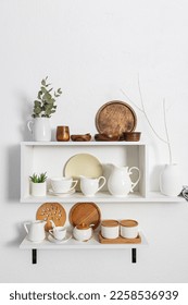 A set of white stylish open shelves with various ceramic white dishes, eco-friendly wooden dishes. white textured wall. kitchen without waste - Shutterstock ID 2258536939
