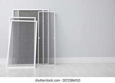 Set of window screens near light grey wall indoors. Space for text