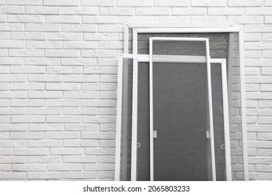 Set of window screens near white brick wall. Space for text