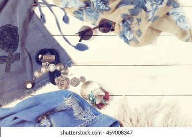 Set of woman clothes and accessories in boho style on white wood background. Top view point. Filtered toned image.