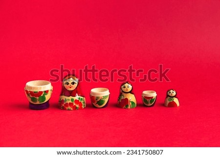A set of wooden matryoshka dolls stand on a red background in order of size