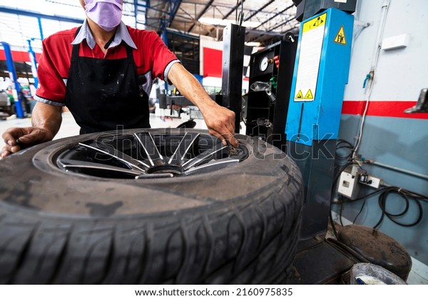 A set of workers\
remove the tire from the rim with a tire-removing machine\
device,Mechanic repairing\
tire
