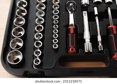 A set of working tools in black plastic bag, a screwdriver, adjustable spanner, sockets for repair on a bamboo, wooden background. Top view