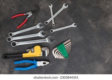 A set of working tools, a hammer, a pliers, a screwdriver, adjustable spanner, sockets for repair on a dark concrete background. Flat lay