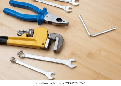 A set of working tools, a hammer, a pliers, a screwdriver, adjustable spanner, sockets for repair on a bamboo, wooden background. Flat lay