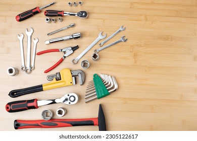 A set of working tools, a hammer, a screwdriver, adjustable spanner, sockets for repair on a bamboo, wooden background. Top view