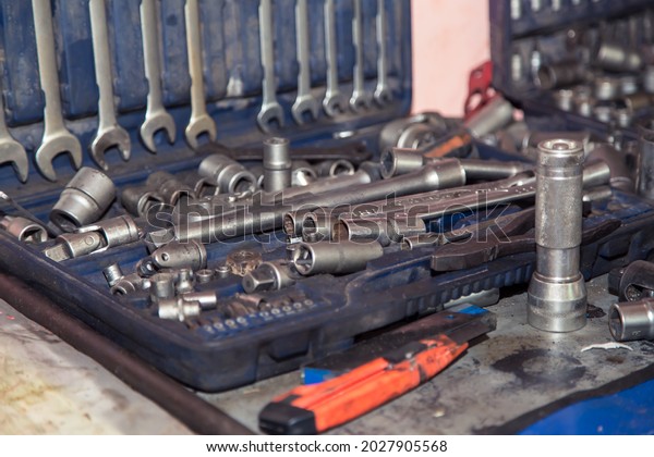 A\
set of wrenches in a case on a metal workbench in the workshop. In\
the garage are tools for repairing broken vehicle parts. Small\
business concept, car repair and maintenance\
service.