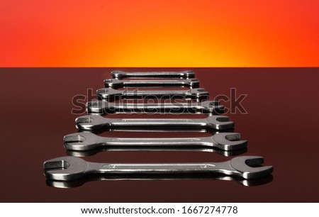 Set of wrenches on a red background. Mirror surface.