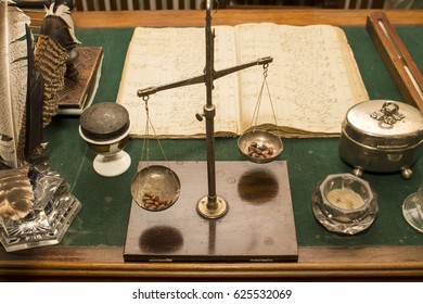 A Set Of Written Antique Accessories And A Scales On An Old Writing Desk