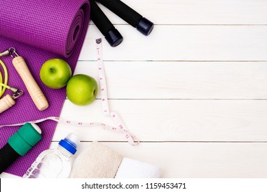 Set Of Yoga Practice With Purple Mat, Dumbbell, Towel, Bottle Of Water And Green Apple, Jump Rope. Exercise Equipment. Top View And Copy Space.