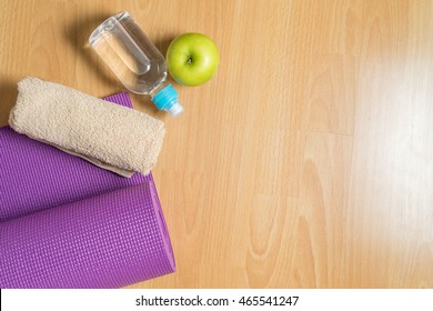 Set For Yoga Practice With Purple Mat, Towel, Bottle Of Water And Green Apple,  Exercise Equipment. Top View And Copy Space.