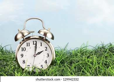 Set your clocks back with this clock in grass against a bright sky. Daylight saving time concept background. - Shutterstock ID 129942332