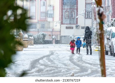 Setif, Algeria - February 28, 2022: Low Angle View Of A Father With His Children Under Snow. Family Having Fun On The Snow Day.