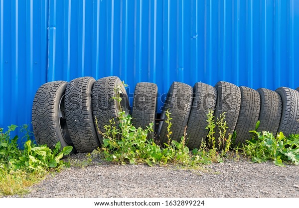 sets of car tires with disks are on\
the street on the ground near the fence of the\
cottage