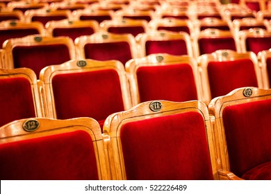 Sets On An Empty Theatre, Taken With Selective Focus And Shallow Depth Of Field. Empty Vintage Red Seats With Numbers, Teather Chair, Cinema Seats. Movie Theater Auditorium With Lines Of Red Chairs.