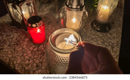 Setting the cemetery candles on fire. Grave candles on the grave during the all saints day. Cemetery on all souls day. - Shutterstock ID 2384566875