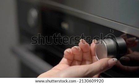 Setting cook modes and oven temperature. Cooking, baking. LCD display of kitchen appliances. White numbers and symbols on a black background. Woman turning switch button, turn on.