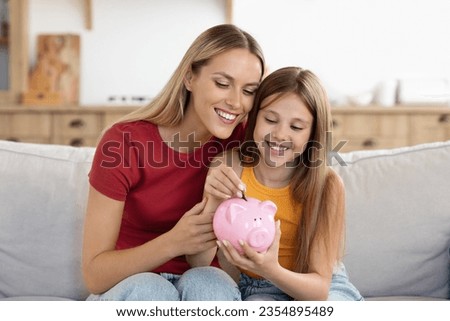 Setting good example. Young parent mother teach child little daughter girl to manage finances save money spend earnings with economy plan family budget. Friendly mom and kid thrift coins in piggybank