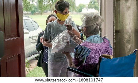 Setting a great example this mother who is part of a volunteer food delivery program takes her children along with her to deliver food to an elderly woman in a wheelchair.