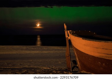 The setting moon over the Baltic Sea and the green aurora in Poland, Debki