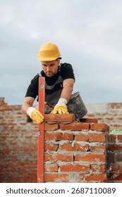 Setting the right level with special leveling tool. A builder is working at the construction site at daytime.