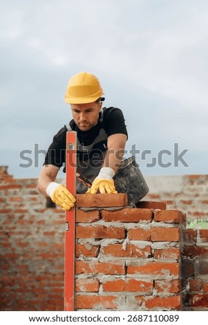 Setting the right level with special leveling tool. A builder is working at the construction site at daytime.