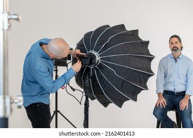 Setting Up Soft Box Lighting On Video Production Set. Behind The Scenes Of A Video Shoot. Interview Of Business Man Dressed Professionally 