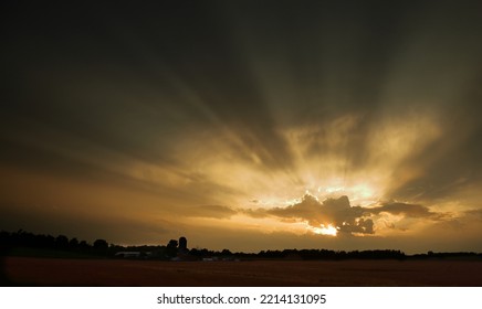 Setting Sun Before A Storm And Light Rays Beaming From Behind Clouds.