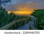 A setting sun behind the deckwalk leading to Bean Point on Holmes Beach at Anna Maria Island, Florida