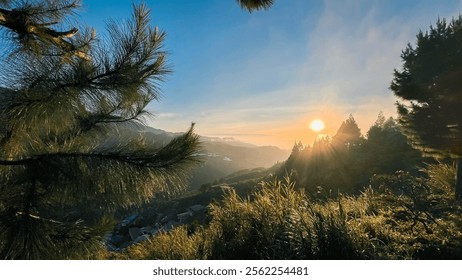 The setting sun behind the mountain casts a serene orange glow, creating a peaceful ambiance.