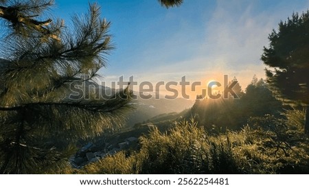 The setting sun behind the mountain casts a serene orange glow, creating a peaceful ambiance.