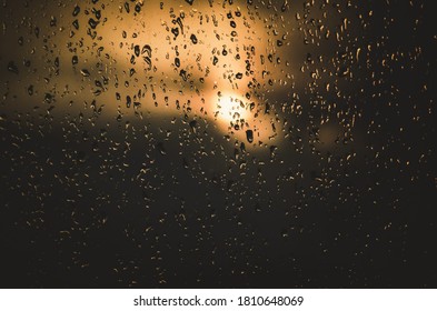 The setting sun behind a rainy window.