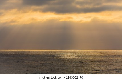 As The Setting Sun Breaks Through A Small Hole In The Atmosphere And Thick Clouds, A Spotlight Appears On The Pacifc Ocean And The Particles Of Light Spread Out In An Angelic, Godly Display Of Beauty