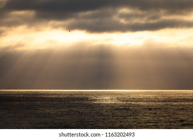 As The Setting Sun Breaks Through A Small Hole In The Atmosphere And Thick Clouds, A Spotlight Appears On The Pacifc Ocean And The Particles Of Light Spread Out In An Angelic, Godly Display Of Beauty