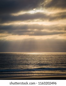 As The Setting Sun Breaks Through A Small Hole In The Atmosphere And Thick Clouds, A Spotlight Appears On The Pacifc Ocean And The Particles Of Light Spread Out In An Angelic, Godly Display Of Beauty