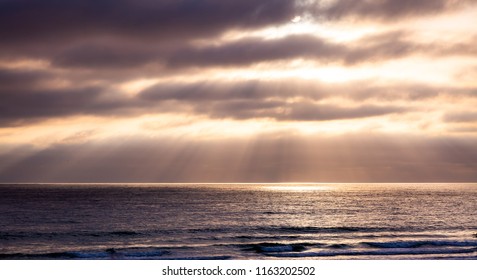 As The Setting Sun Breaks Through A Small Hole In The Atmosphere And Thick Clouds, A Spotlight Appears On The Pacifc Ocean And The Particles Of Light Spread Out In An Angelic, Godly Display Of Beauty