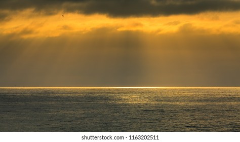 As The Setting Sun Breaks Through A Small Hole In The Atmosphere And Thick Clouds, A Spotlight Appears On The Pacifc Ocean And The Particles Of Light Spread Out In An Angelic, Godly Display Of Beauty