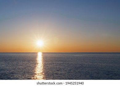 The setting sun goes into the sea on the horizon with a light track and reflections on the sea. Free space