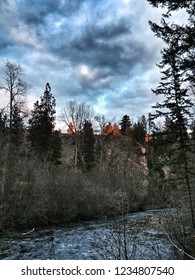 The Setting Sun Illuminates A Select Few Trees In The Distance Behind The Creek Forged Canyon