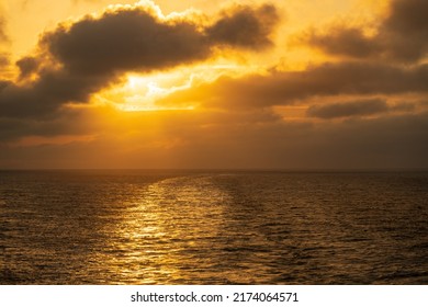 Setting Sun Illuminating The Clouds Over The Wake Of A Cruise Ship Sailing Down The Coastline Of Alaska