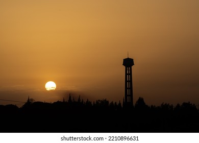 Setting Sun From Left Side Of Water Tower Silhouette, Sunset